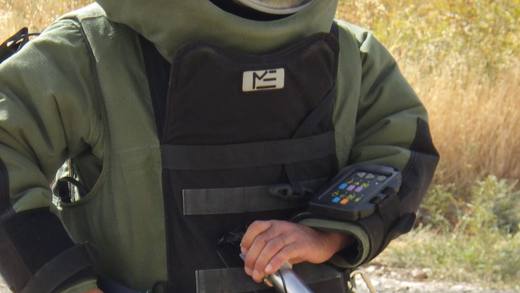 Démineur en tenue EOD progressant avec un détecteur